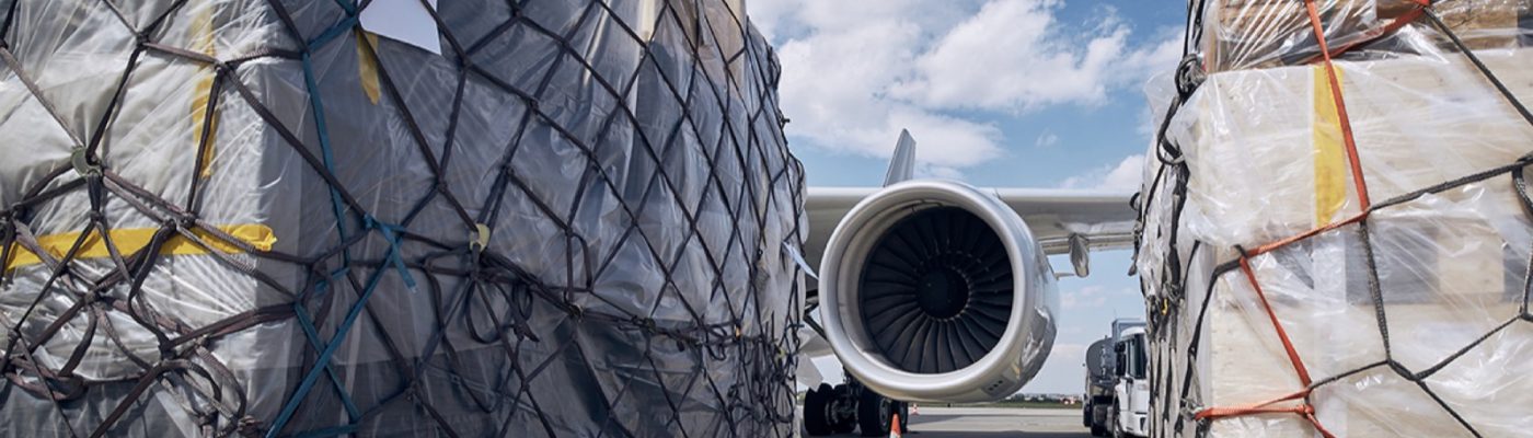 Preparation before flight. Loading of cargo containers against jet engine of freight airplane.