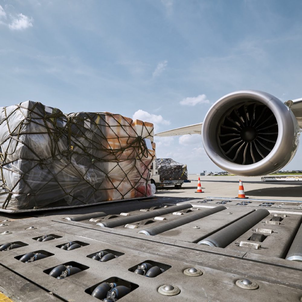Preparation fright airplane before flight. Loading of cargo containers against jet engine of plane.